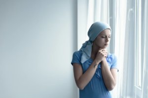 cancer survivor deep in thought standing by the window shutterstock