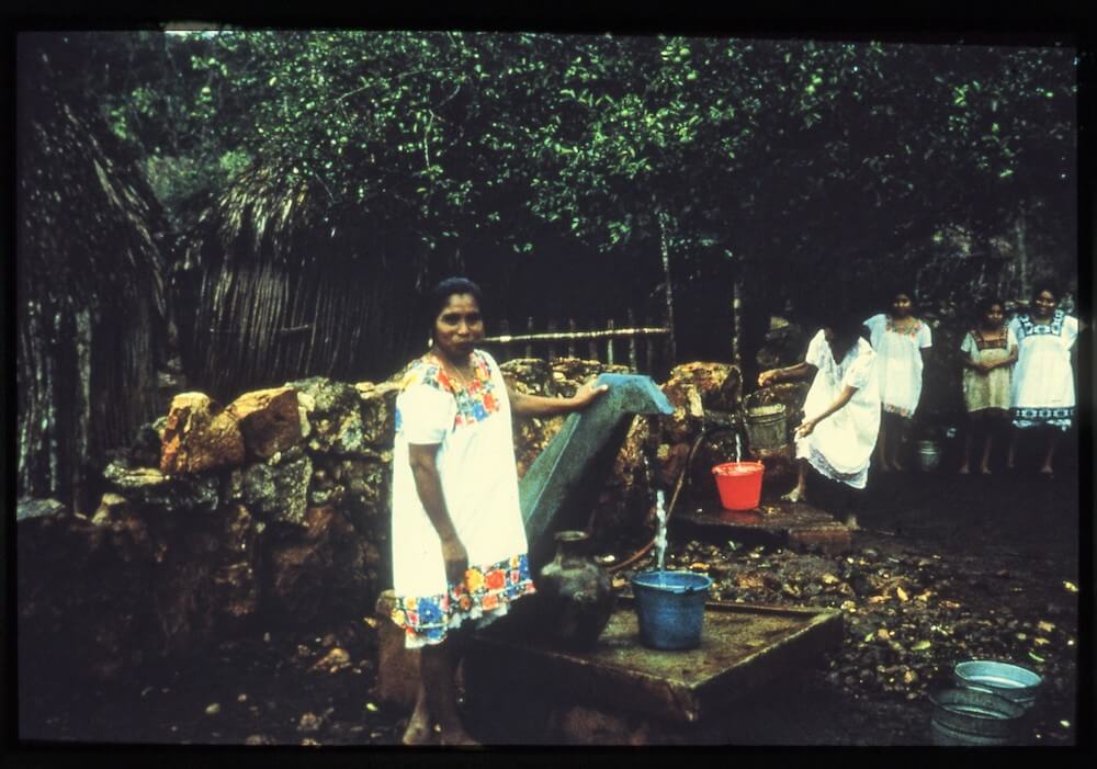 maya women getting water from gas powered pump compressed