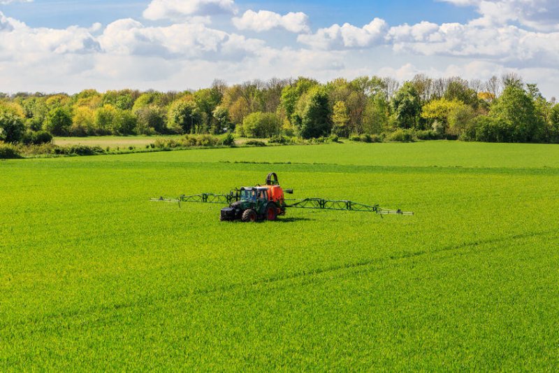Tractor spraying glyphosate pesticides on a corn field