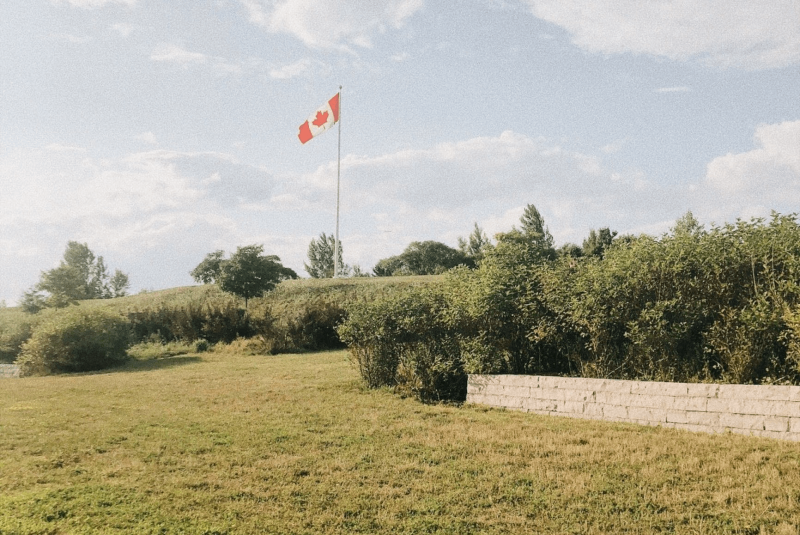 free photo of a canadian flag flying over a grassy field