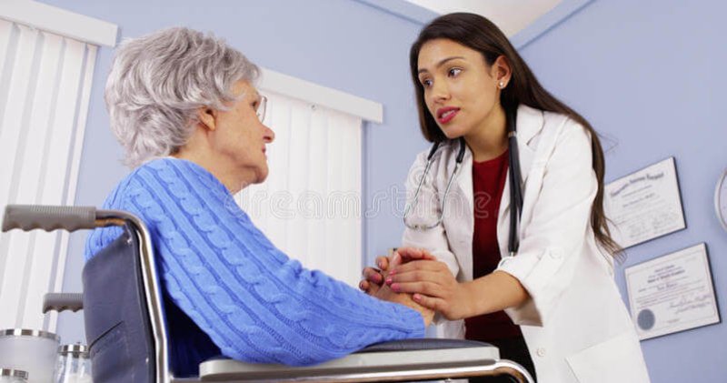 hispanic woman doctor comforting disabled elderly patient mexican women