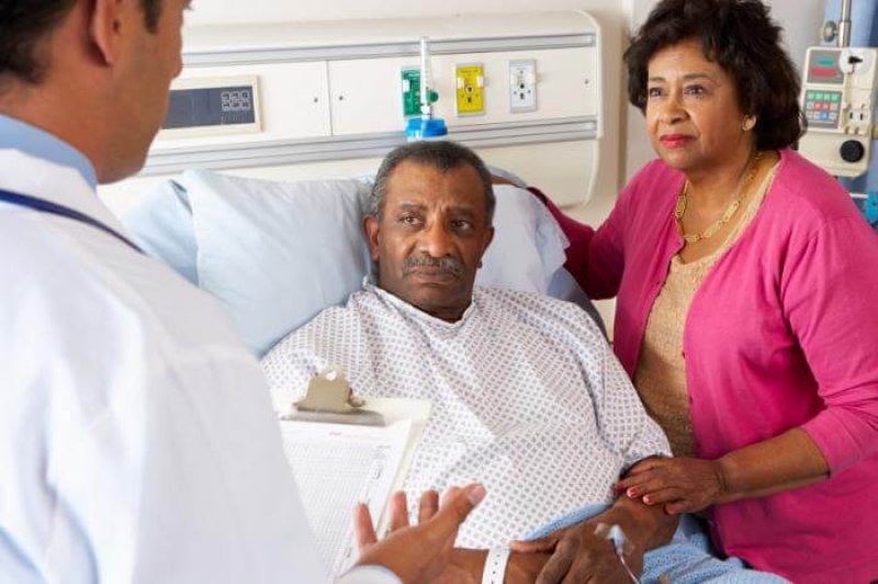 patient in hospital bed speaking to doctor and partner