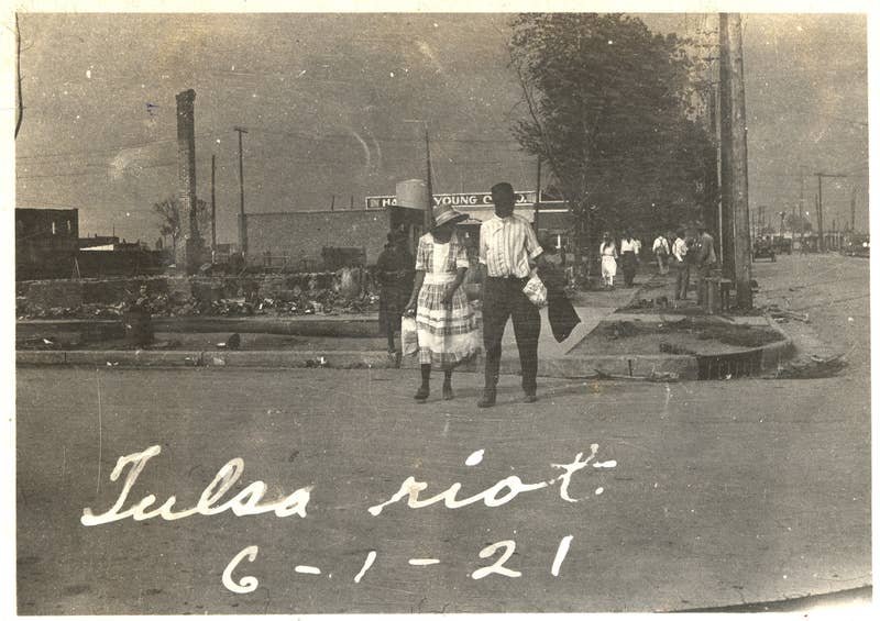 A couple walks across the street with smoke rising in the distance after the Tulsa massacre in June 1921. Credit: Oklahoma Historical Society/Getty Images