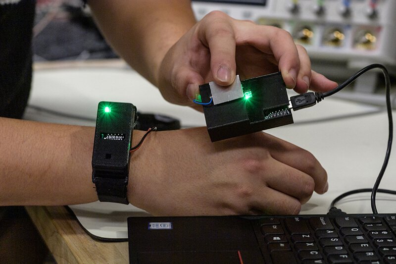 A researcher transfers information from a chip in a watch by touching a sensor connected to a laptop. Credit: John Underwood/Purdue University