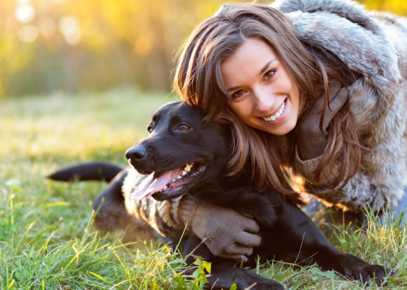 woman with dog black labrador smiling grass sunshine